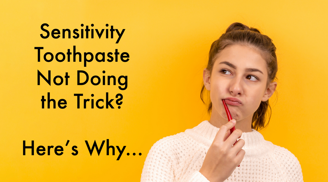 Woman with white sweater and red toothbrush in mouth on yellow background with black overlay text reading "Sensitivity Toothpaste Not Doing The Trick? Here's Why..."