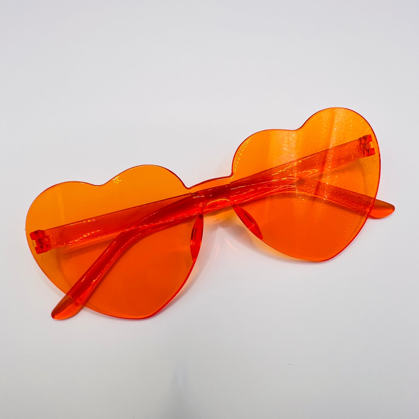 A pair of heart-shaped orange protective eyewear with visible red edges.