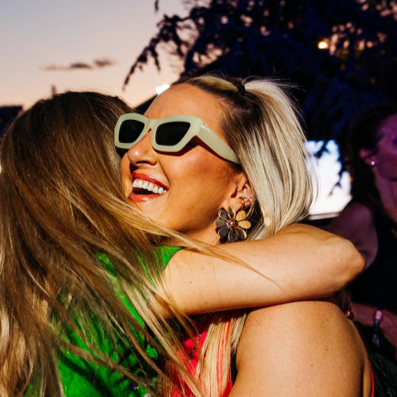 Woman smiling while hugging friend at music festival - The Whitening Store website home page.