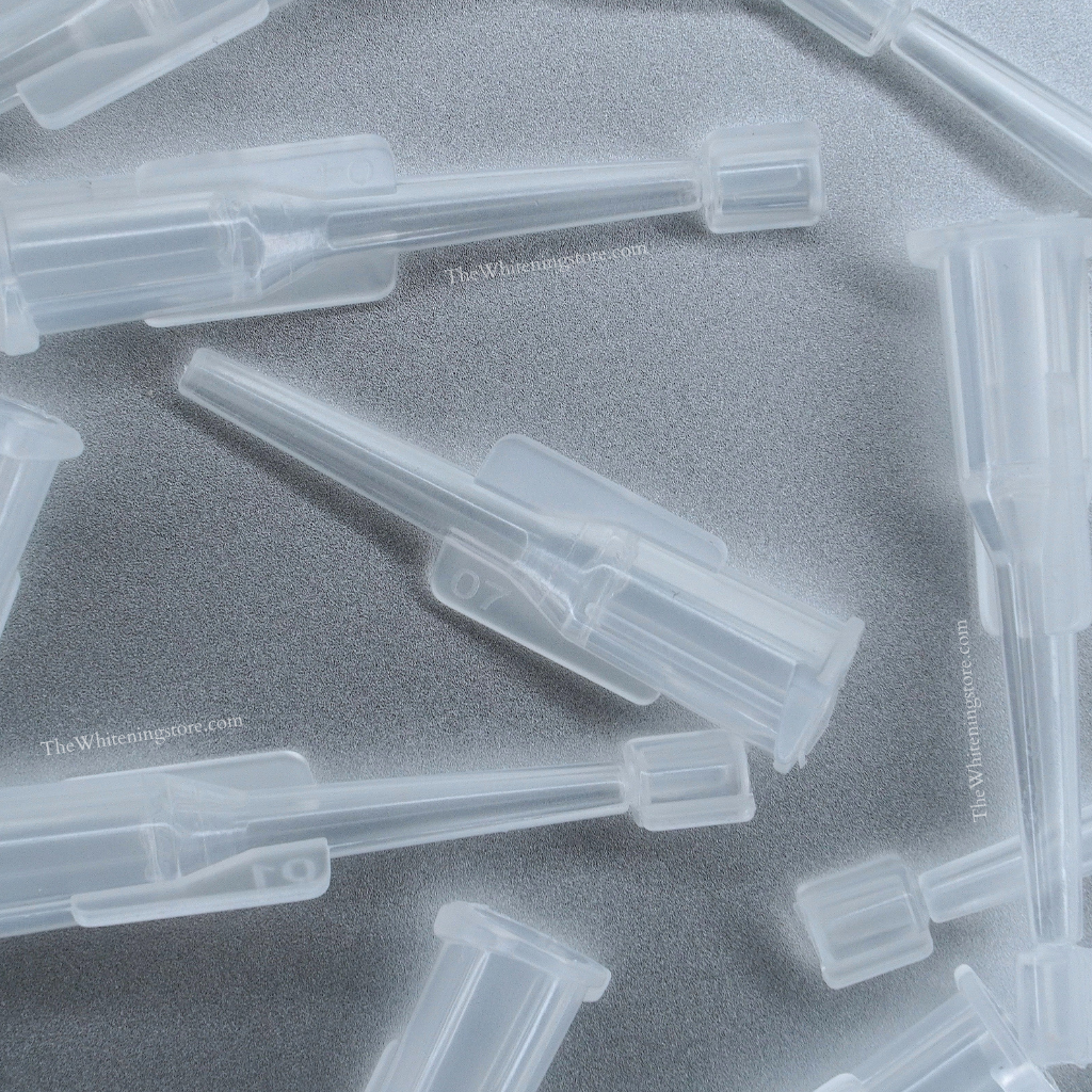 Clear plastic find point dental syringe tip components on a gray background.