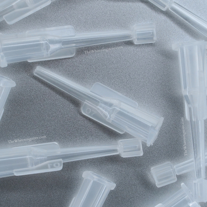 Clear plastic find point dental syringe tip components on a gray background.