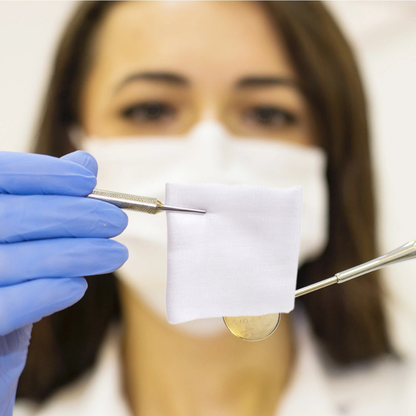 Person wearing a face mask and gloves holding a small container with a dropper.