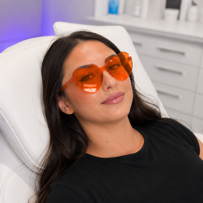 Woman wearing orange-tinted heart-shaped glasses in a clinical setting