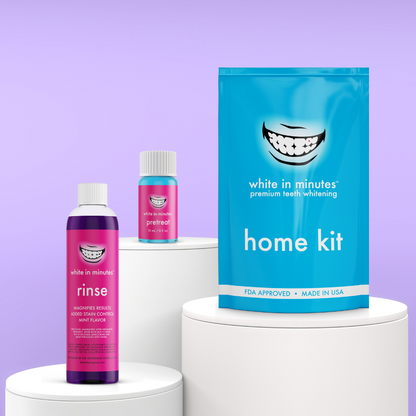 Front-facing display of White in Minutes Everyday Radiance Set on white pedestals with purple backdrop, which includes a home whitening kit, purple mouthwash and stain-lifting pretreat.